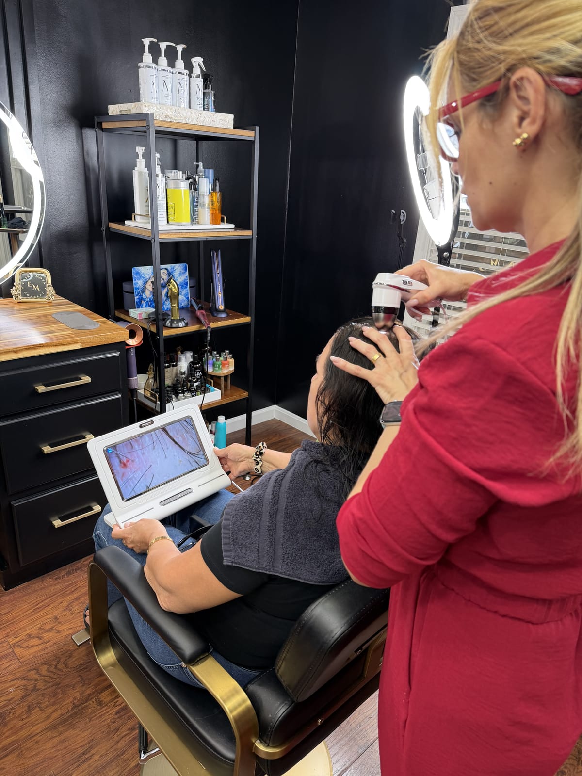 Erika fazendo análise do couro cabeludo com câmera, com a imagem ampliada na tela
