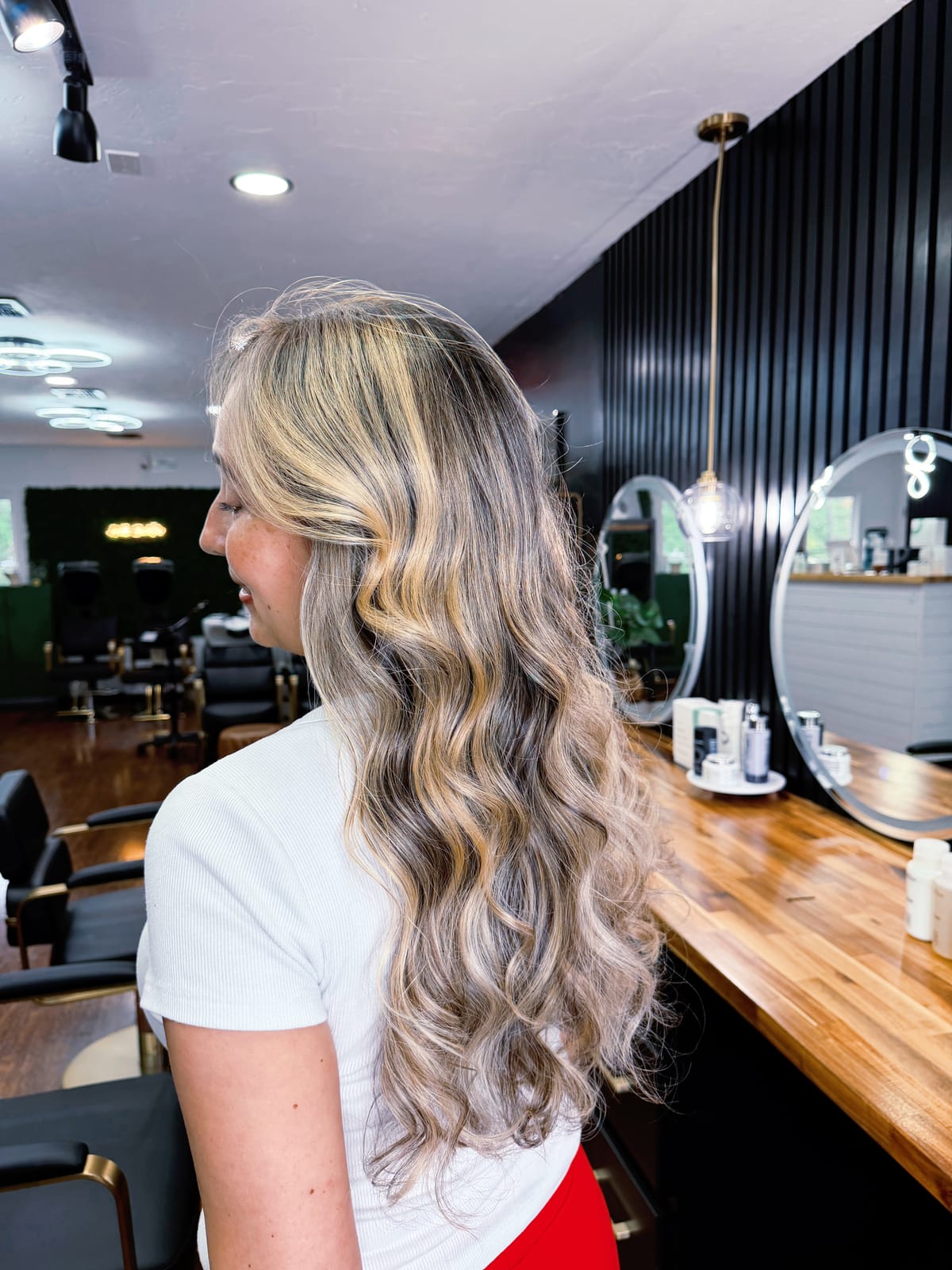 Cliente de perfil com loiro iluminado e ondas no salão