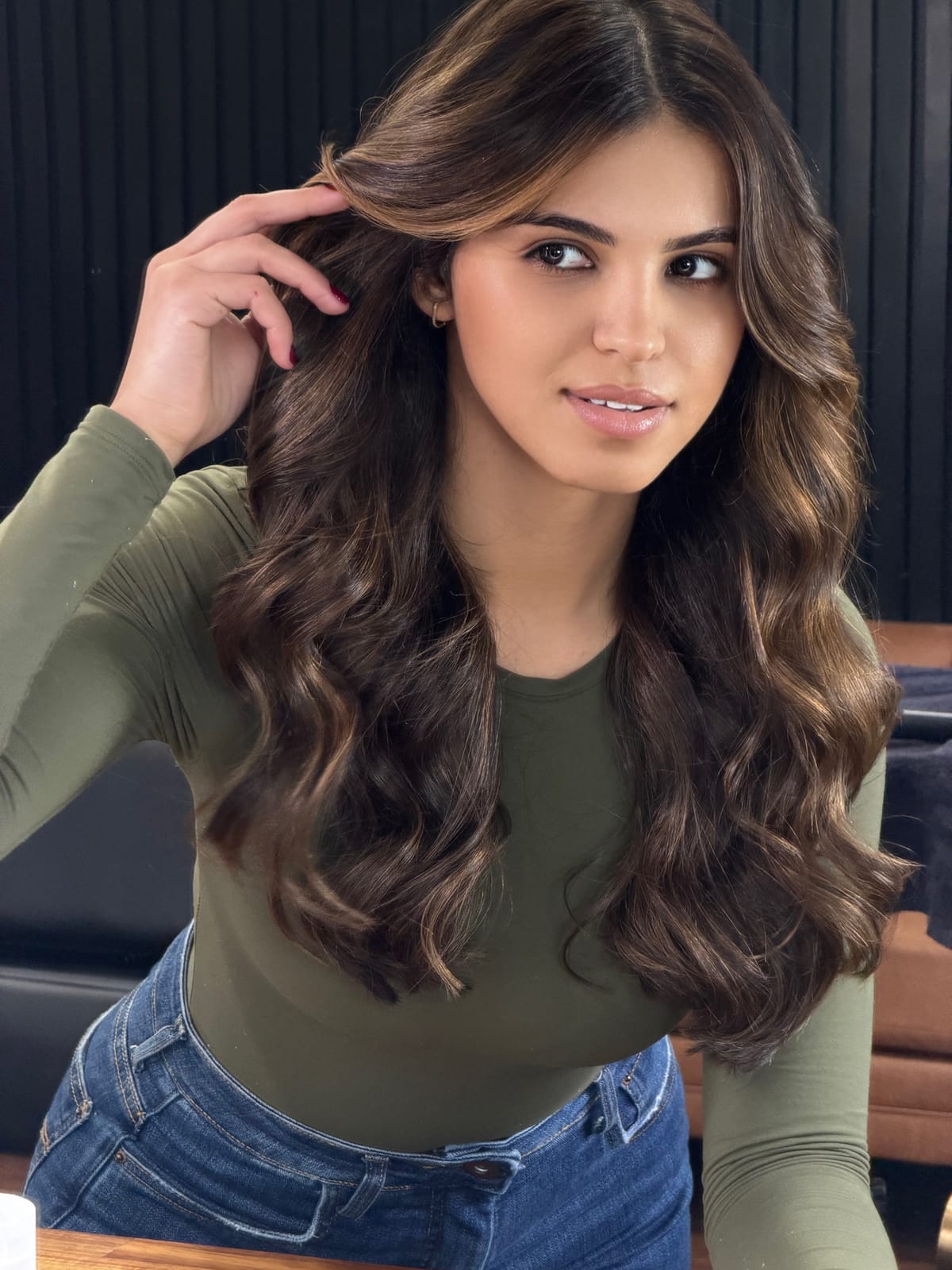 Cliente com morena iluminada longa, com a mão no cabelo