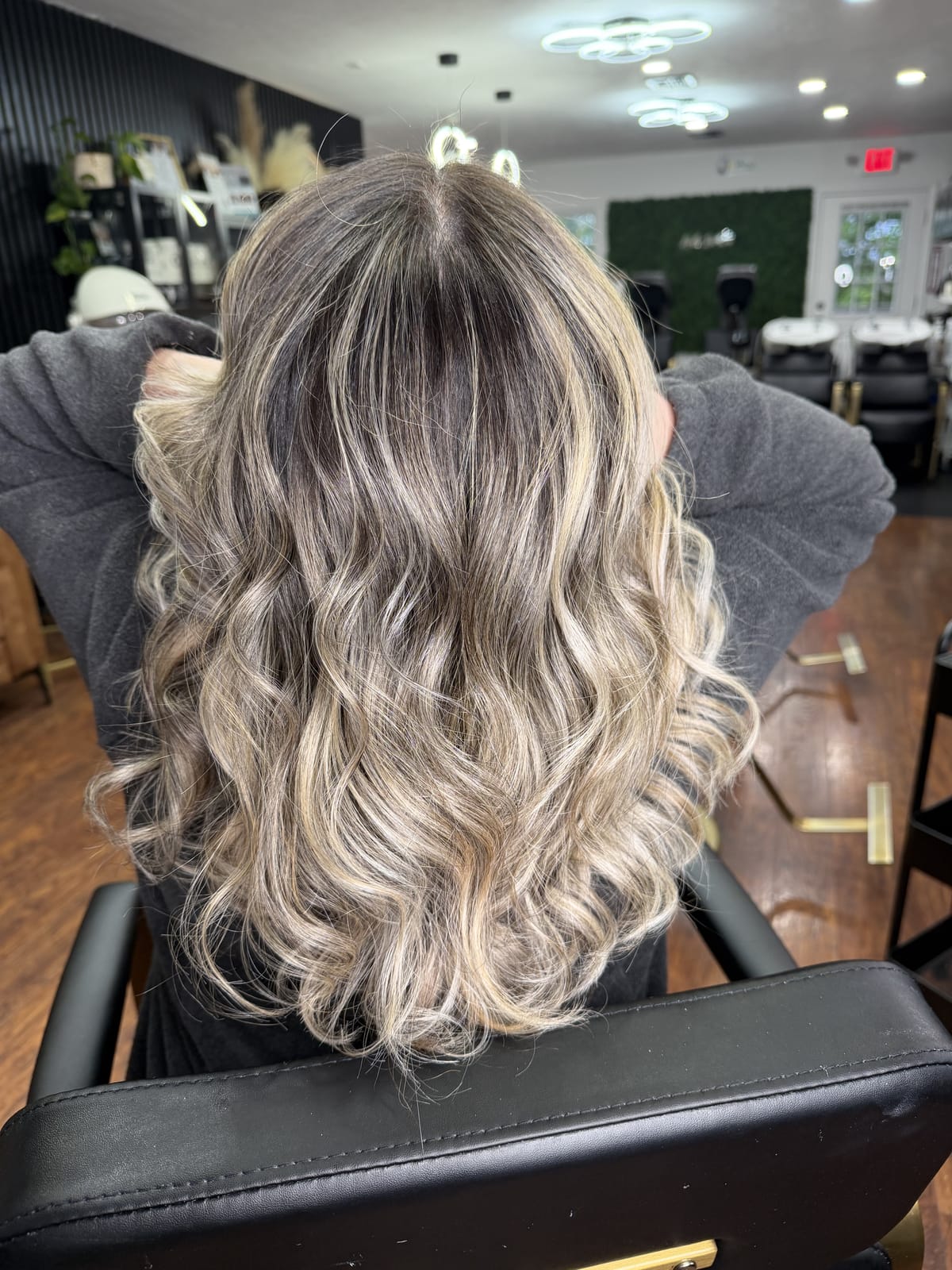 Mechas loiras com raiz esfumada, vistas de costas na cadeira do salão